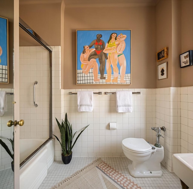 993 Park Ave Unit 11A, New York City, NY 10028 - full bathroom featuring tile walls, tile patterned floors, wainscoting, and combined bath / shower with glass door