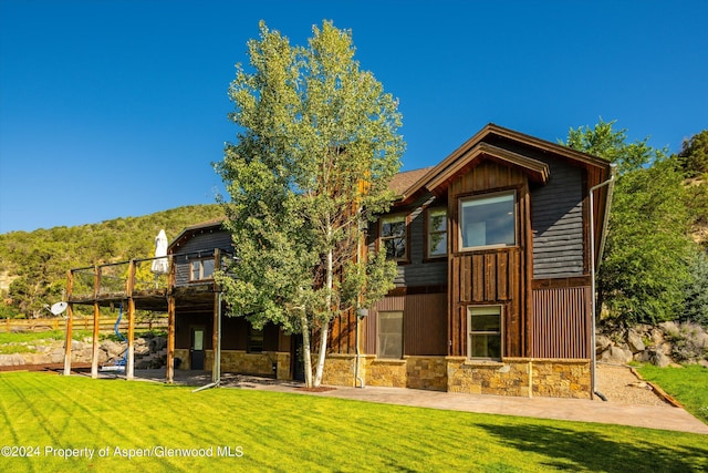 313 Cerise Ranch Rd, Carbondale, CO 81623 - rear view of property featuring stone siding, a deck, and a yard