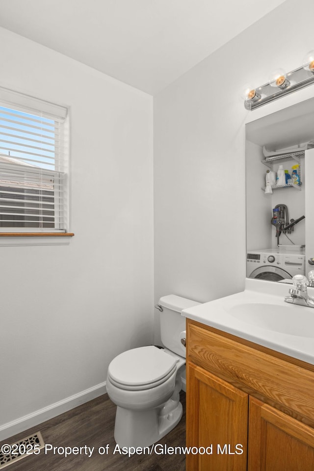 half bathroom featuring washer / clothes dryer, baseboards, toilet, vanity, and wood finished floors