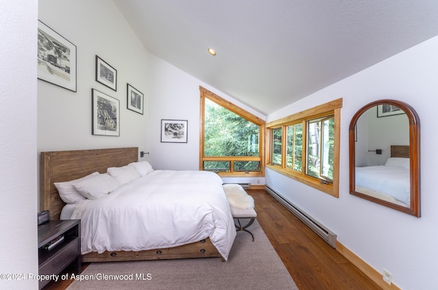 bedroom with dark hardwood / wood-style flooring, vaulted ceiling, and a baseboard heating unit