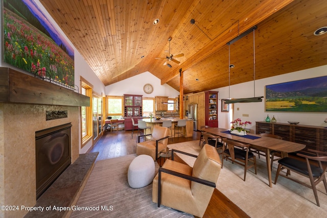 dining room featuring ceiling fan, a tile fireplace, wood-type flooring, high vaulted ceiling, and wooden ceiling