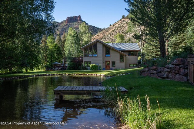 rear view of house with a lawn and a water and mountain view