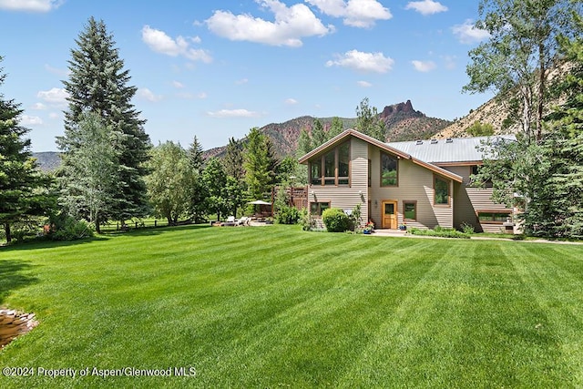 rear view of property featuring a lawn and a mountain view