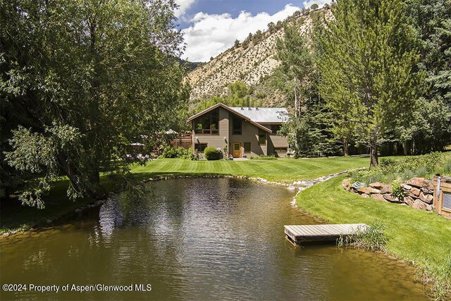 view of dock featuring a lawn and a water and mountain view