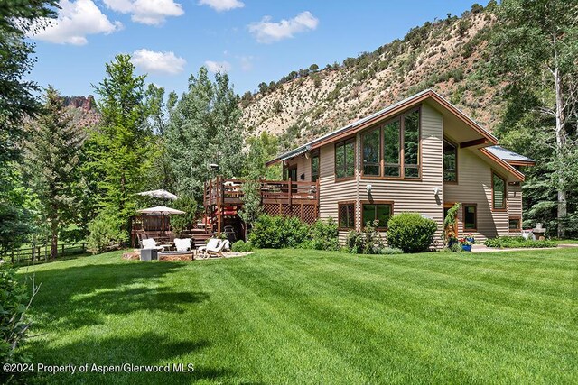 exterior space with a deck with mountain view and a lawn