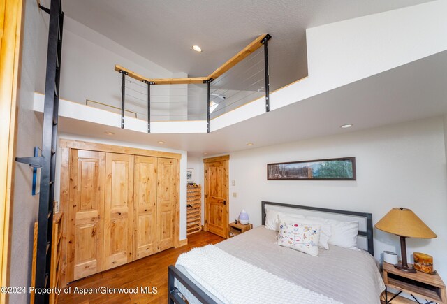 bedroom with a high ceiling, a closet, and wood-type flooring