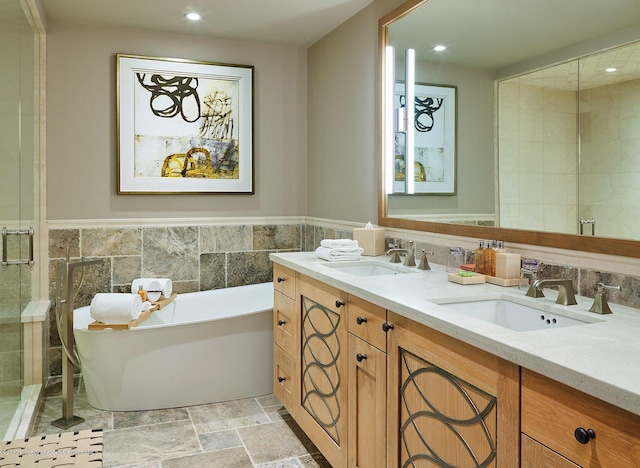 bathroom featuring recessed lighting, a sink, a freestanding bath, and stone finish floor
