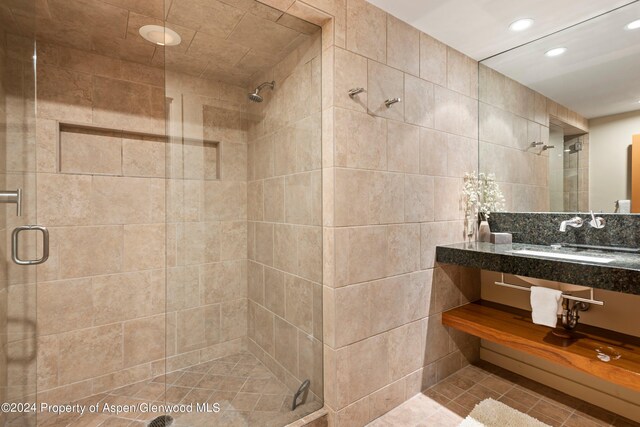 bathroom featuring tile walls, tile patterned floors, a shower with door, and sink