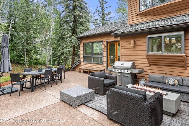 view of patio with area for grilling and an outdoor living space with a fire pit