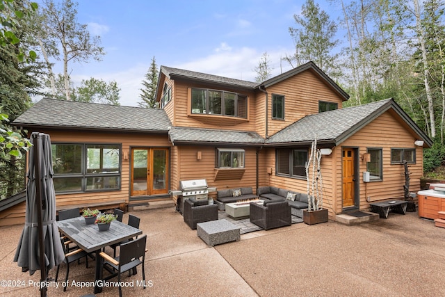 back of property with a hot tub, an outdoor living space with a fire pit, and a patio area