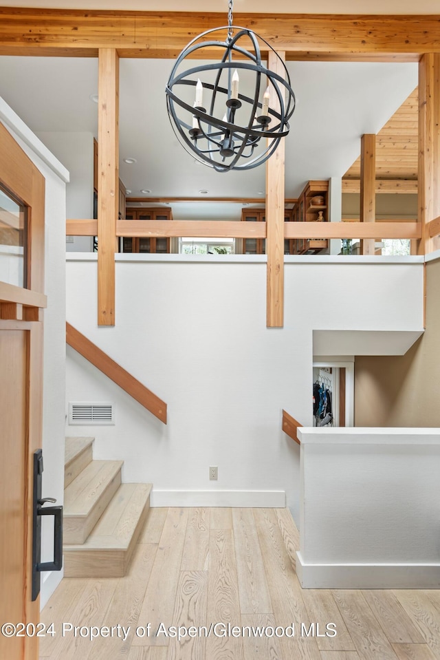 staircase featuring wood-type flooring and a notable chandelier