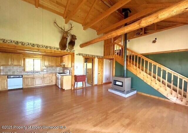 unfurnished living room featuring high vaulted ceiling, stairway, beamed ceiling, wooden ceiling, and dark wood-style flooring