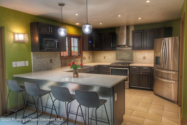 572 E Main St, New Castle, CO 81647 - kitchen with appliances with stainless steel finishes, wall chimney range hood, a peninsula, tasteful backsplash, and a kitchen bar