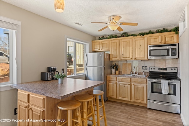 1101 Village Rd Unit Ll3B, Carbondale, CO 81623 - kitchen with appliances with stainless steel finishes, light brown cabinetry, ceiling fan, decorative backsplash, and a textured ceiling