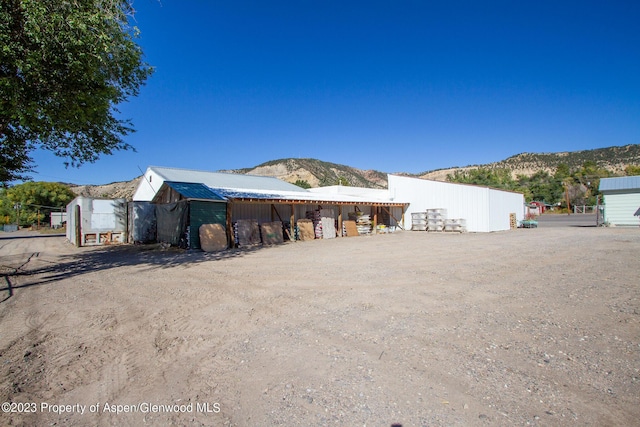 view of side of home featuring a mountain view and an outdoor structure