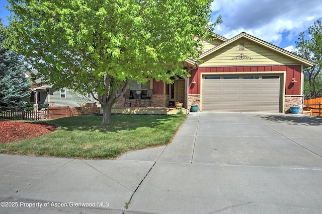 view of front of home featuring board and batten siding, fence, stone siding, and concrete driveway