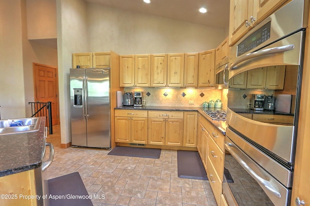 kitchen with light brown cabinetry, high vaulted ceiling, appliances with stainless steel finishes, and decorative backsplash