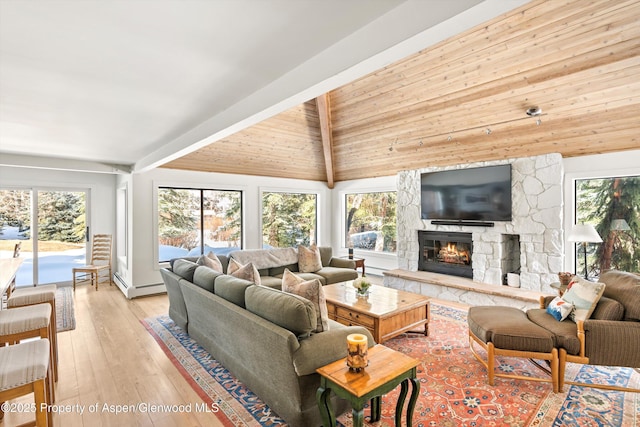 living room featuring a stone fireplace, vaulted ceiling with beams, a healthy amount of sunlight, and light wood finished floors