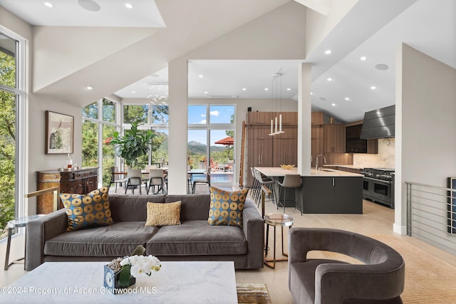 living room featuring plenty of natural light, sink, high vaulted ceiling, and a chandelier