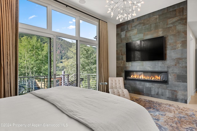 bedroom featuring access to outside, a fireplace, and an inviting chandelier