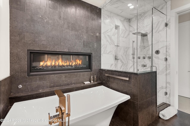 bathroom with plus walk in shower, a tile fireplace, and tile walls