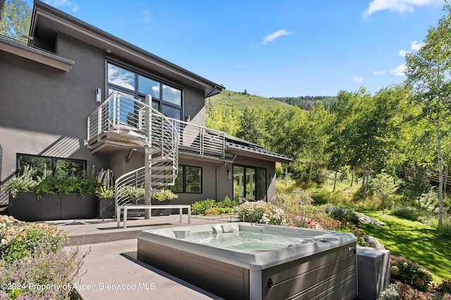 view of patio with a balcony and a hot tub