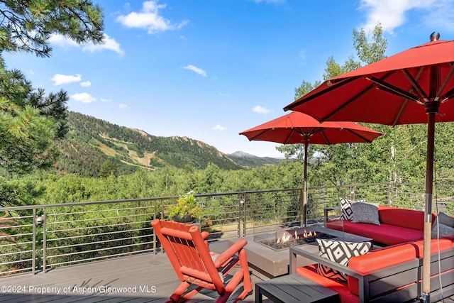 wooden deck with a mountain view and an outdoor living space with a fire pit