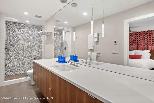 bathroom featuring vanity, toilet, and a tile shower