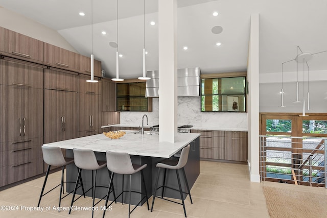 kitchen featuring a large island, tasteful backsplash, light stone counters, vaulted ceiling, and light tile patterned floors