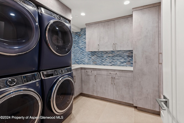 washroom with washing machine and clothes dryer, light tile patterned floors, cabinets, and stacked washer / drying machine