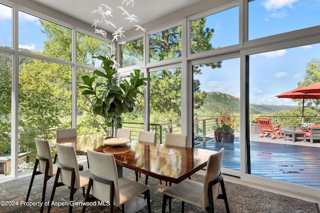 sunroom / solarium featuring a mountain view, a healthy amount of sunlight, and an inviting chandelier