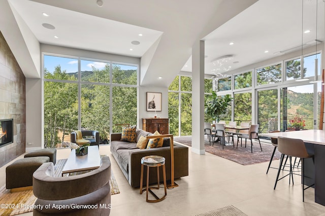 living room with a towering ceiling and a tiled fireplace