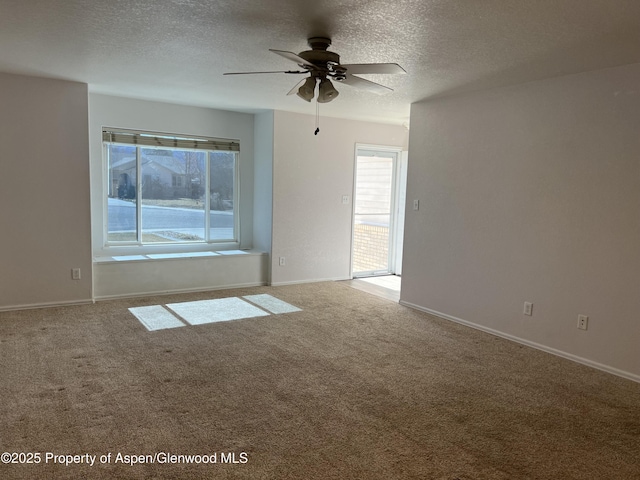 carpeted empty room with baseboards, plenty of natural light, a ceiling fan, and a textured ceiling