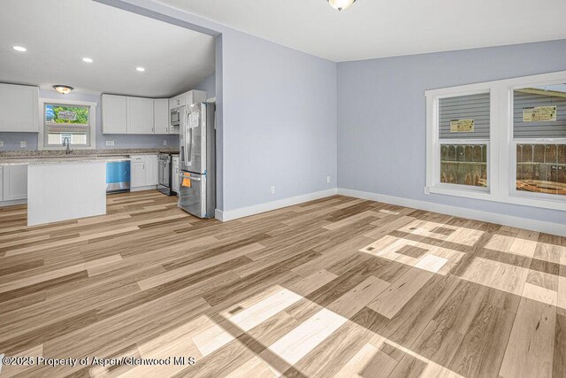 955 Sequoia Ave, Craig, CO 81625 - kitchen with appliances with stainless steel finishes, light wood finished floors, white cabinets, open floor plan, and recessed lighting