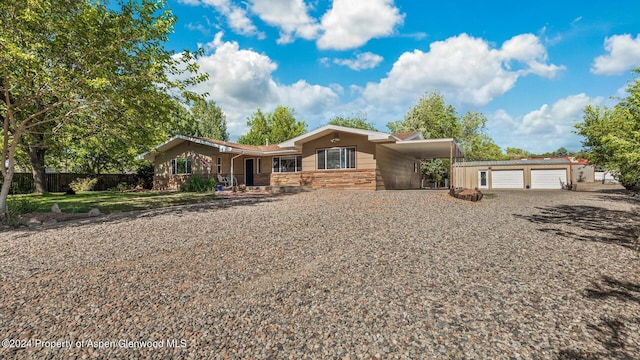 view of front of house featuring a carport, a garage, and an outbuilding