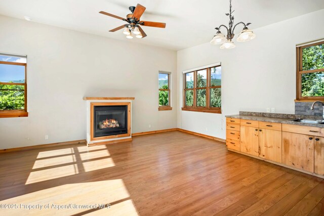 110 Easy St, Carbondale, CO 81623 - unfurnished living room with light wood finished floors, a glass covered fireplace, a chandelier, and a ceiling fan