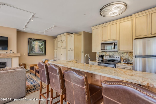 150 Snowmass Club Cir Unit 1623, Snowmass Village, CO 81615 - kitchen featuring stainless steel appliances, track lighting, cream cabinetry, open floor plan, and light stone counters