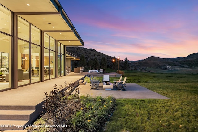 patio terrace at dusk with a mountain view and a yard