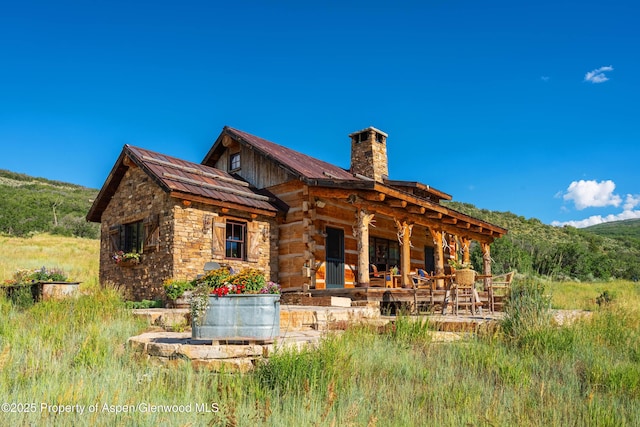 1350 Old Herron Rd, Basalt, CO 81621 - rear view of house featuring a chimney, a mountain view, a metal roof, a patio, and stone siding