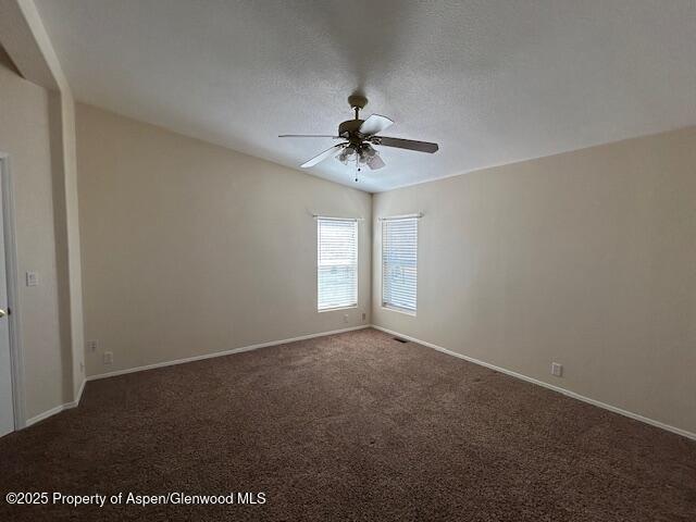 carpeted empty room featuring baseboards, a ceiling fan, and visible vents