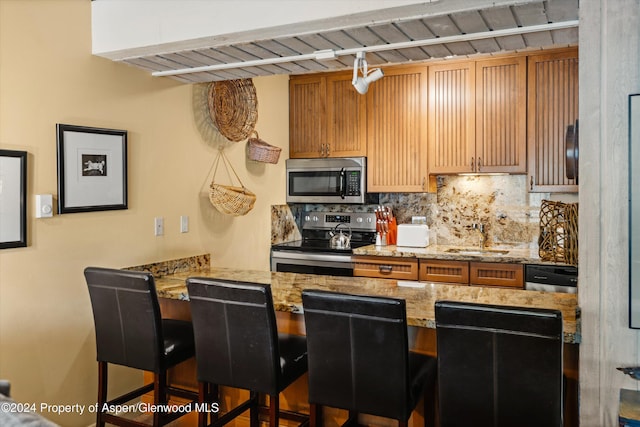131 E Durant Ave Unit 202, Aspen, CO 81611 - kitchen with stainless steel appliances, a sink, backsplash, and a kitchen bar