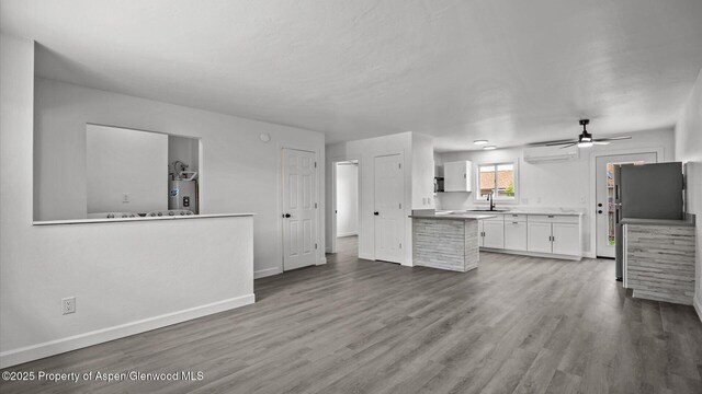 2430 W Ave, Rifle, CO 81650 - kitchen featuring water heater, white cabinets, an AC wall unit, wood finished floors, and ceiling fan