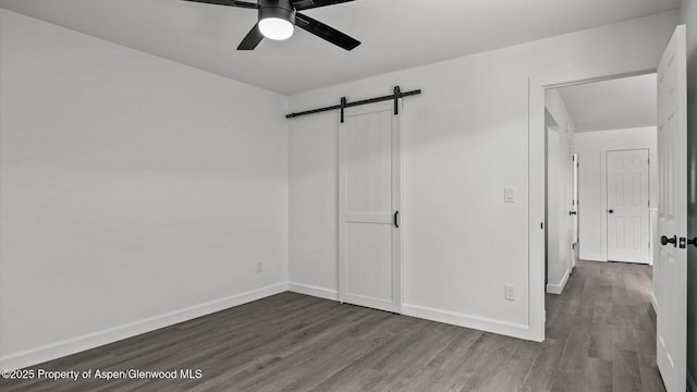2430 W Ave, Rifle, CO 81650 - unfurnished bedroom featuring wood finished floors, a barn door, and ceiling fan