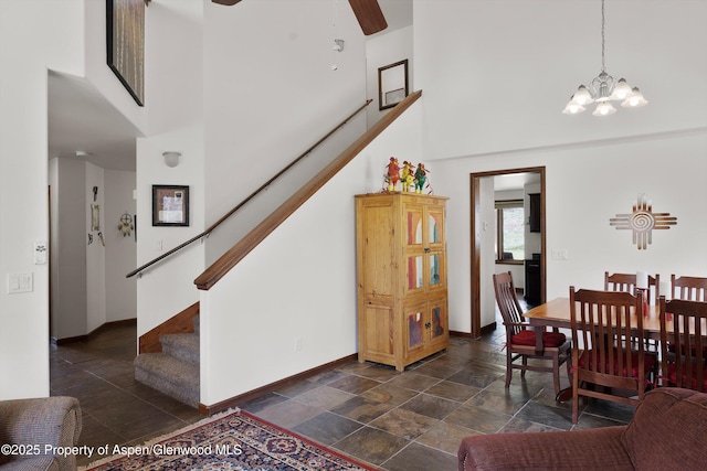 entrance foyer with baseboards, stone finish flooring, stairs, and a high ceiling