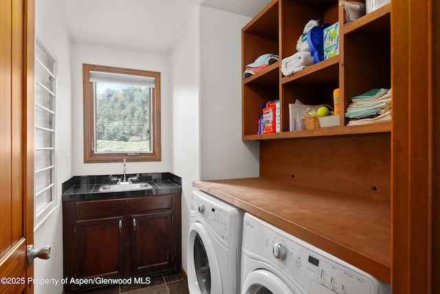 clothes washing area with a sink, washing machine and dryer, and cabinet space