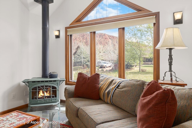 living room featuring baseboards, lofted ceiling, a wealth of natural light, and a wood stove