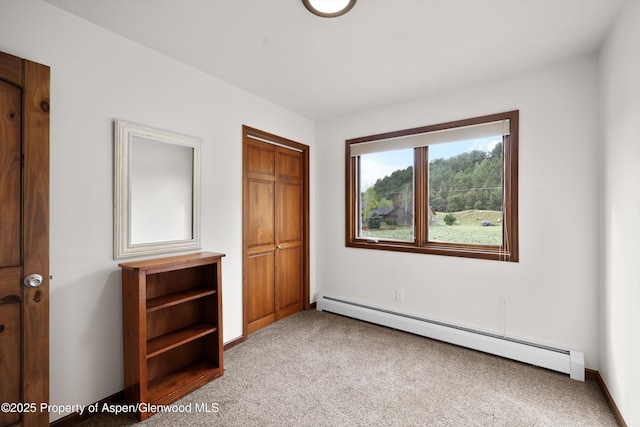 unfurnished bedroom with a closet, carpet, and a baseboard heating unit