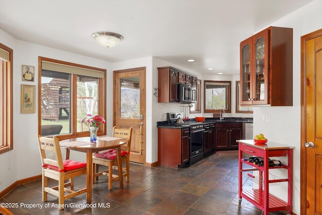 kitchen featuring baseboards, glass insert cabinets, dark countertops, and stainless steel appliances