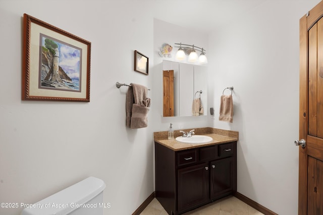 half bath featuring baseboards, tile patterned floors, toilet, and vanity