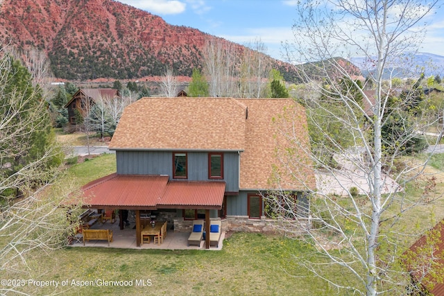 exterior space with a yard, a patio, a mountain view, and stone siding